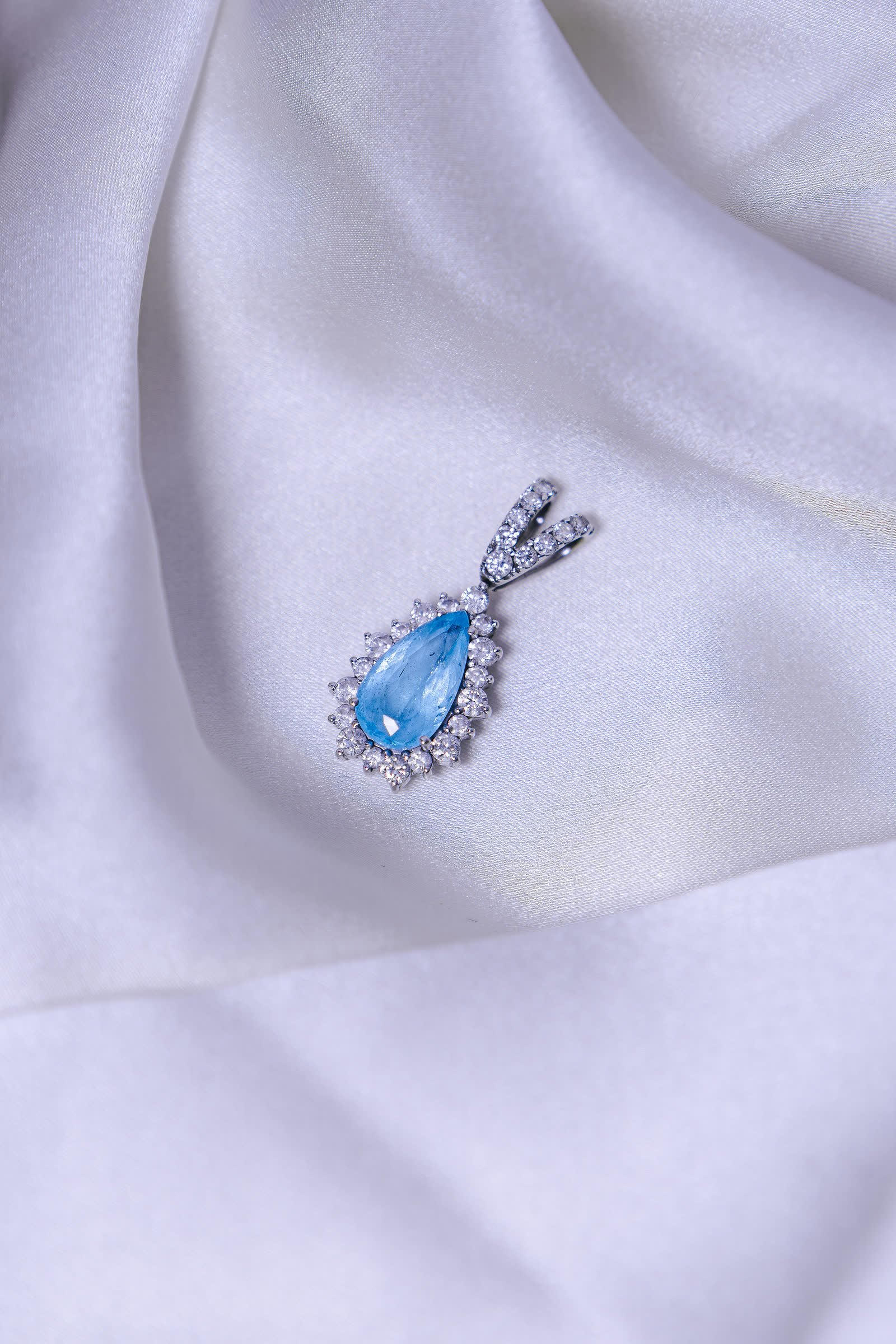 Aquamarine Drop Pendant — A pear-cut aquamarine under a diamond halo.