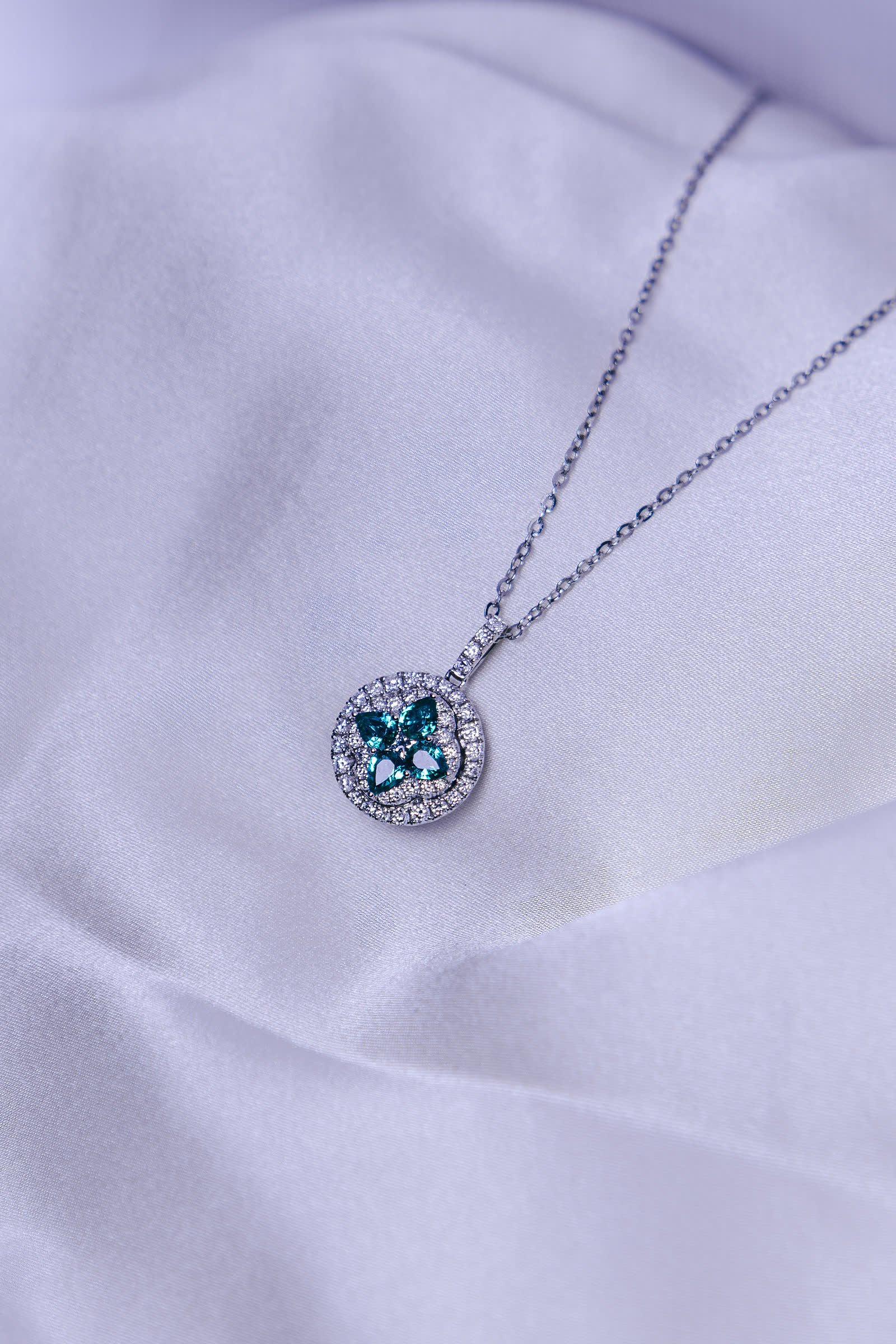 Clover Pendant — An emerald clover inside a round double halo.