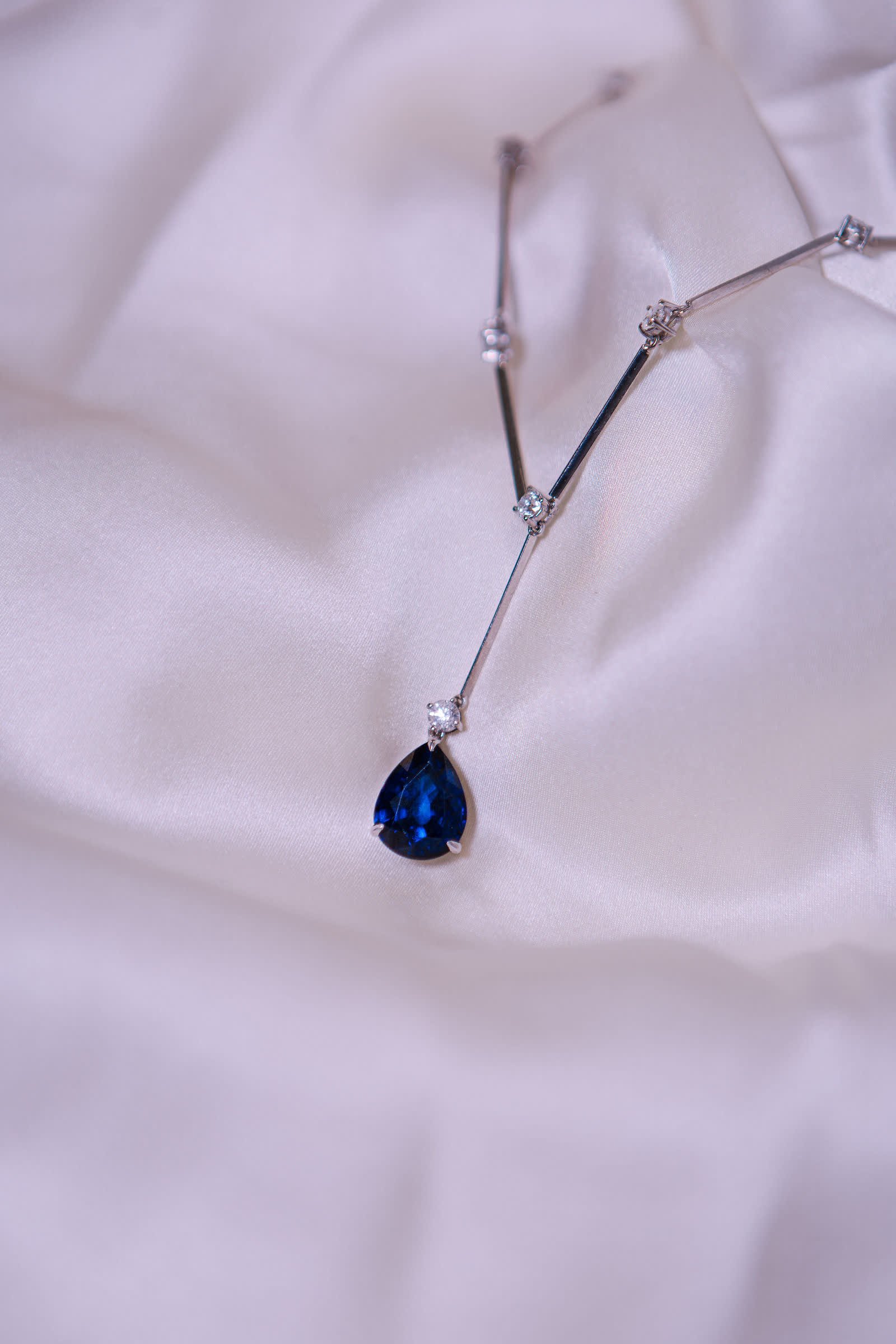 Sapphire Drop Necklace — A pear-cut sapphire hung from a bar-and-diamond chain.